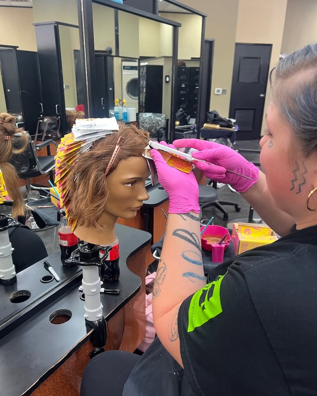A student in pink gloves packs foils into a mannequin head in class